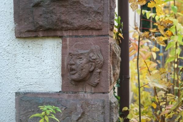 Farbfoto einer Mauer mit Steinquadern, eines davon mit eingehauener Maske