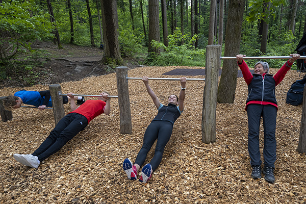 Vier Personen verschiedener Generationen treiben Sport in einem Bewegungspark im Wald