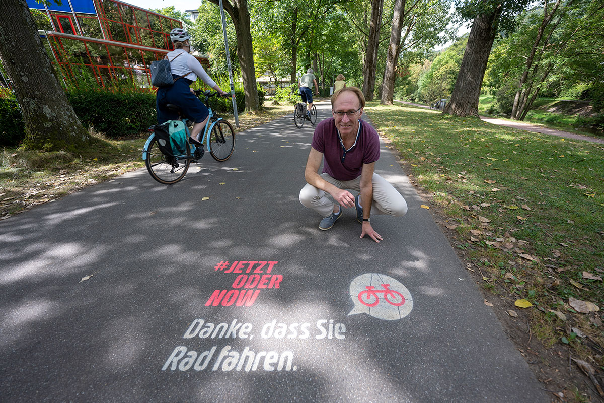 Baubürgermeister Prof. Dr. Martin Haag präsentiert auf einem Radweg die Dankesbotschaft an die Radfahrenden
